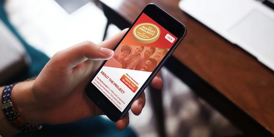 The Market Project app on an iphone held by a user.
